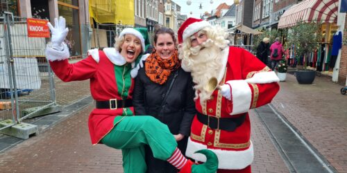 De Singing Santa komt samen met zijn helper de Kerstelf. En het publiek gaat graag samen op de foto. In het midden een Purmerendse dame.