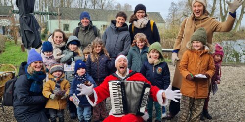 Een groep leden van Natuurmonumenten op de foto met de kerstman en zijn accordeon. Na de foto speelt hij weer live kersmuziek.