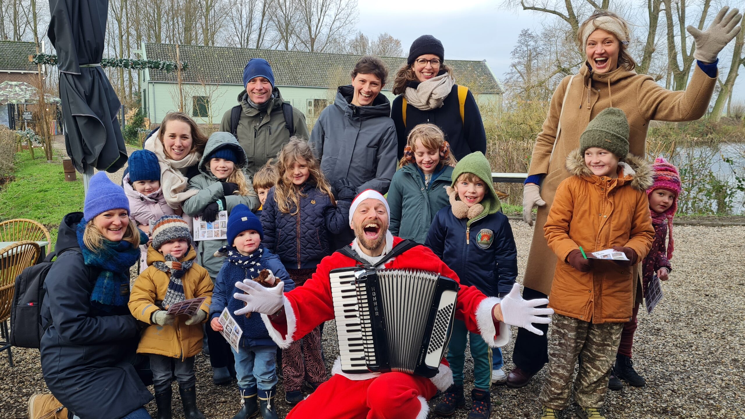 Een groep leden van Natuurmonumenten op de foto met de kerstman en zijn accordeon. Na de foto speelt hij weer live kersmuziek.