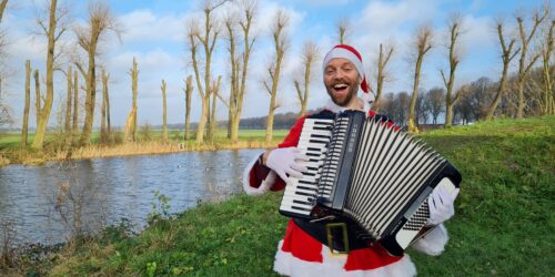 Accordeonist speelt verkleed als Kerstman live Kerstliedjes.