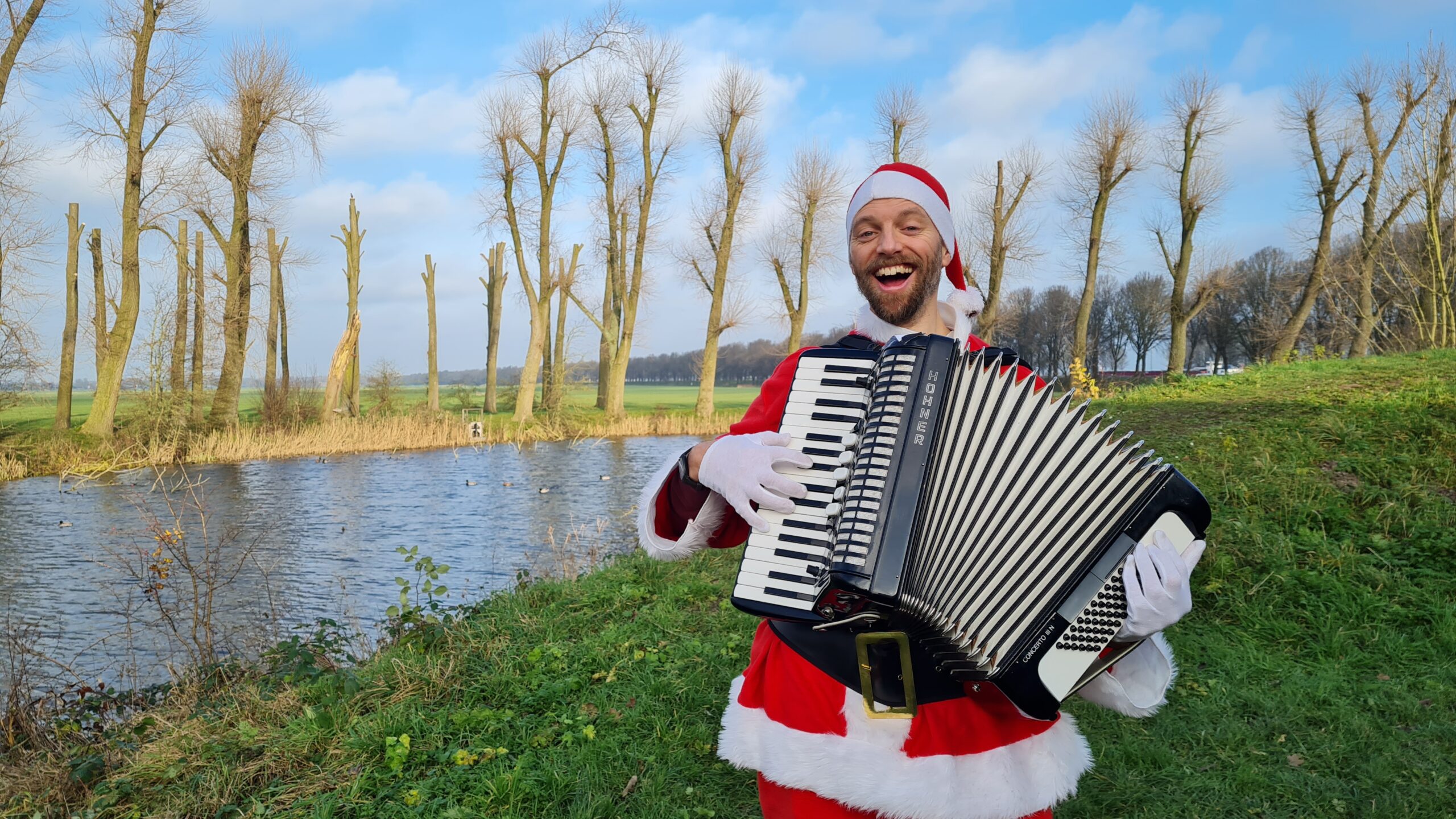 Accordeonist speelt verkleed als Kerstman live Kerstliedjes.