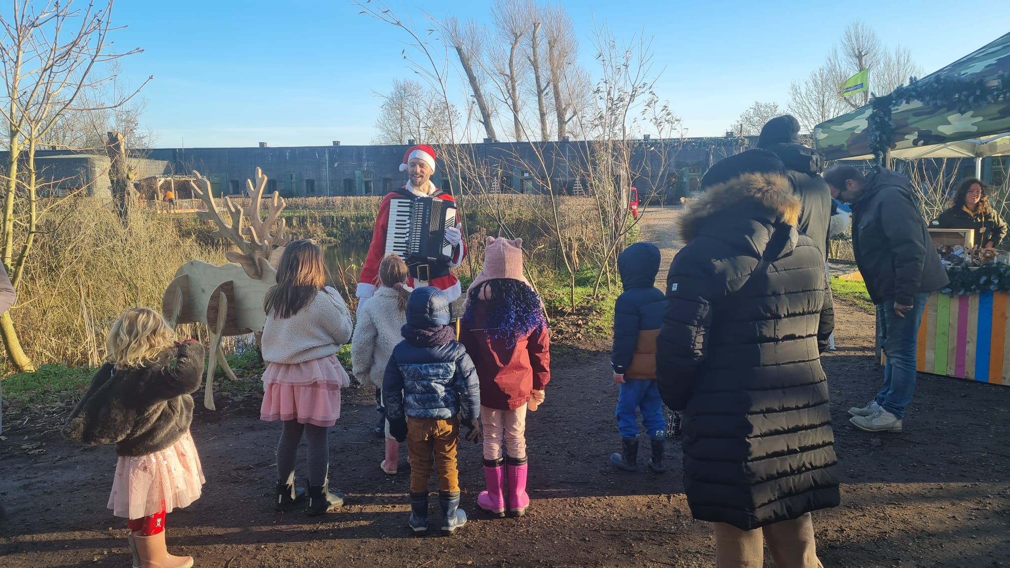 De Kerstman speelt liedjes voor jong en oud. Hier vermaakt hij een groepje kinderen met live kerstmuziek op een event van Natuurmonumenten.