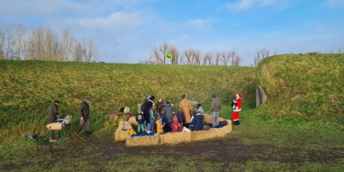 Kerstman zingt live kerstmuziek bij kampvuur op een event van Natuurmonumenten.